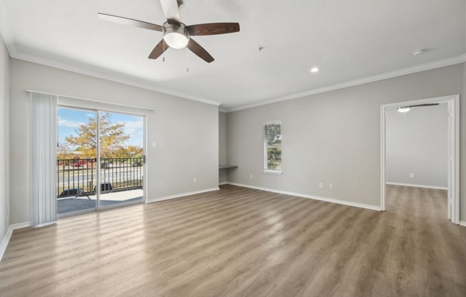 an empty living room with a ceiling fan and a window