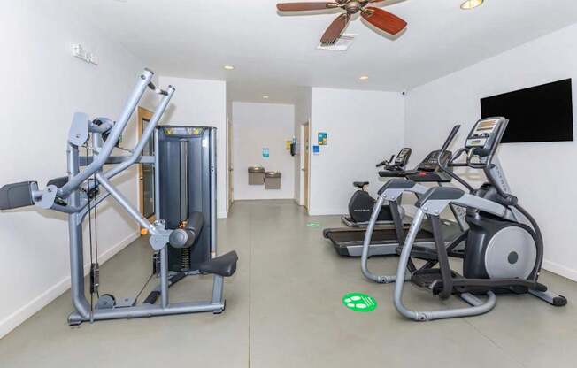 A gym with a row of treadmills and a weight machine.