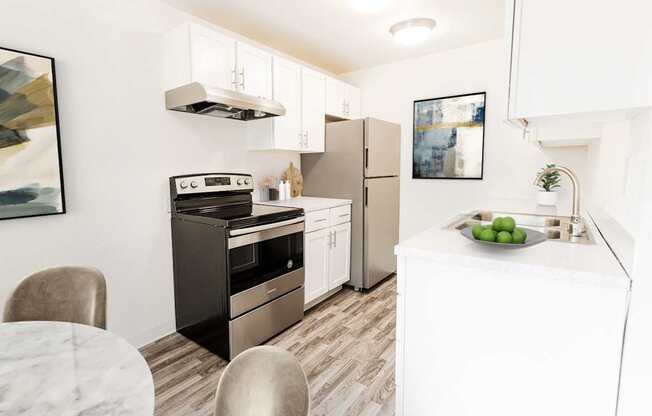 A modern kitchen with a stove, refrigerator, and a table with chairs.