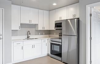 a white kitchen with stainless steel appliances and white cabinets