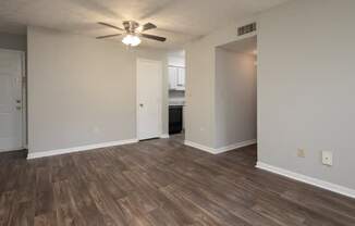 A room with a ceiling fan and wood flooring.