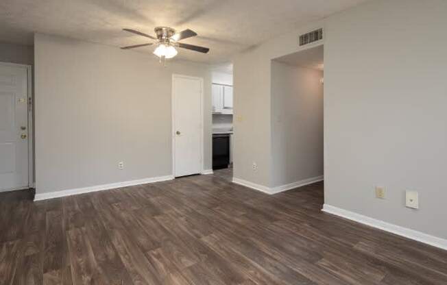 A room with a ceiling fan and wood flooring.