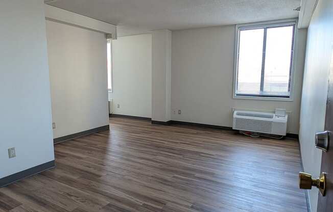 an empty living room with wood floors and a window