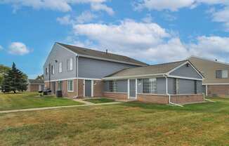 Exterior apartment building at Farmbrooke Manor Apartments in Clinton Township MI with well-kept landscaping and on-site parking