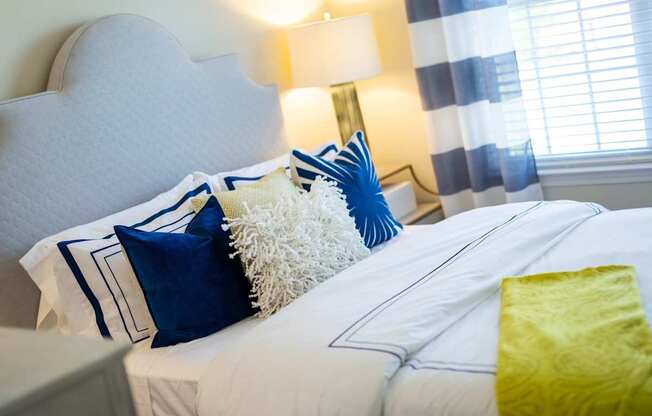 A bed with white sheets and blue and white pillows.