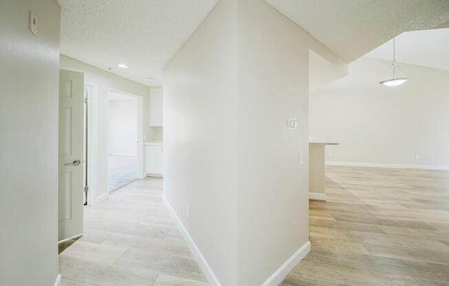 A spacious room with light-colored walls and a wooden floor.