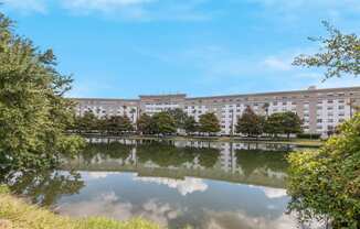 a large building is reflected in the water in front of a pond