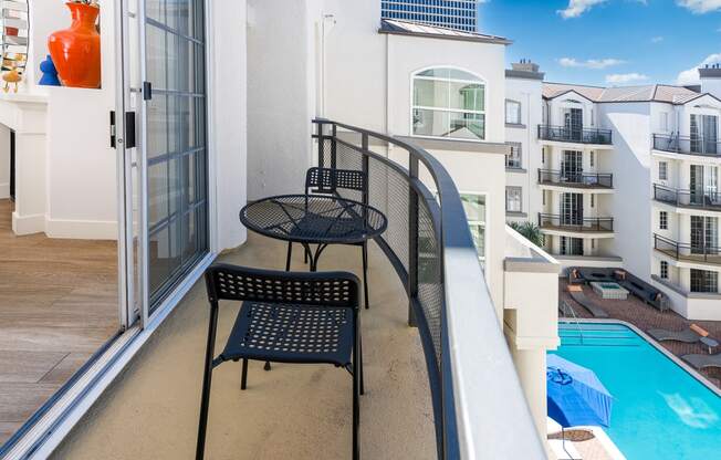 two chairs on a balcony overlooking a pool and an apartment building