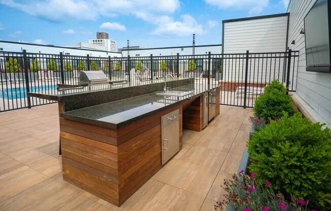 a rooftop entertaining area with a grill and a pool