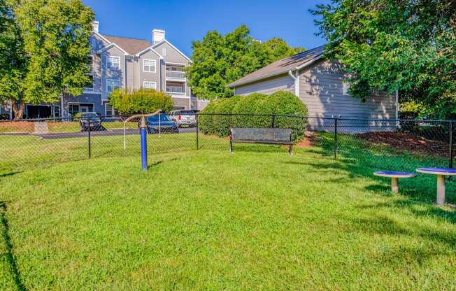 A grassy area with a bench and a fence in front of a building.