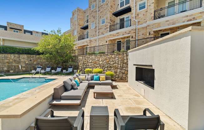 A poolside patio with chairs and a stone wall.
