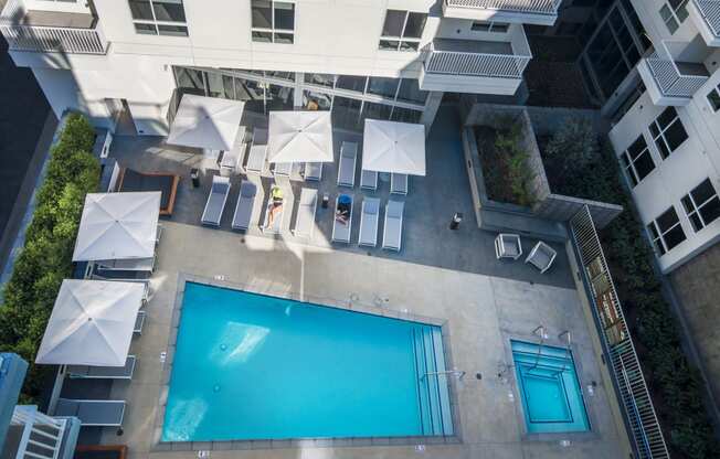 a pool is surrounded by chairs and umbrellas in an apartment building