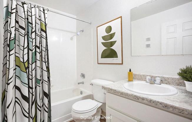 An upgraded bathroom with a toilet, a sink, and a shower curtain at Hampton Lakes Apartments, Michigan, 49534