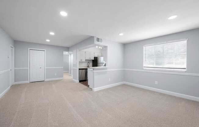 A spacious room with a kitchenette and a window with blinds.