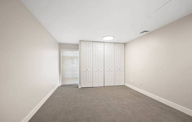 A room with a grey carpet and a white wardrobe.