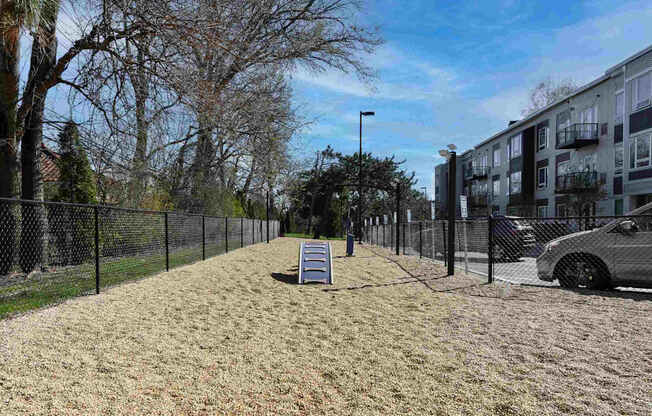 A residential area with a fenced yard and a car parked on the side.