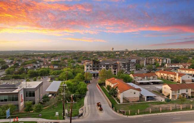 A sunset view of a residential area with houses and a road.