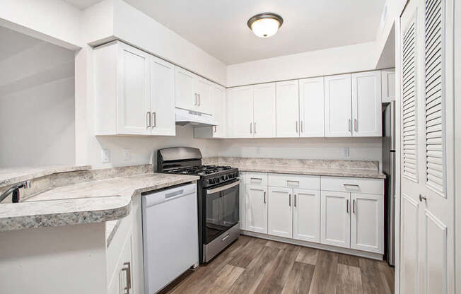 A kitchen with white cabinets and a marble countertop.