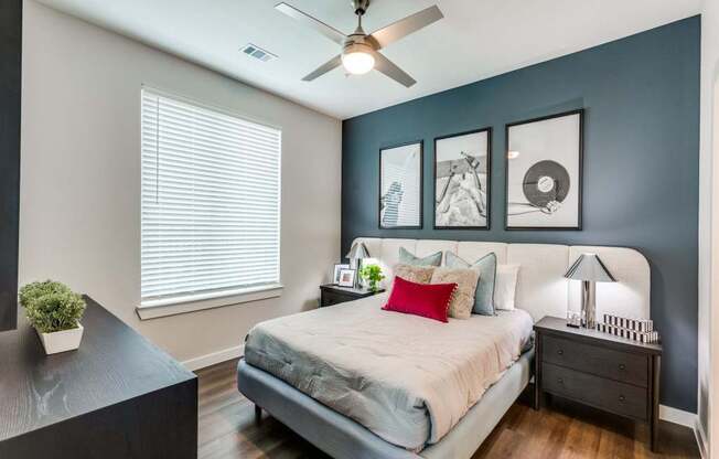 A bedroom with a bed, nightstand, and a ceiling fan.