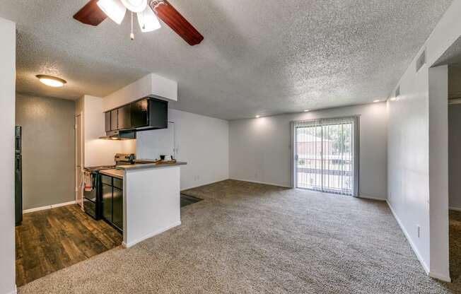 an empty living room and kitchen with a door to a balcony