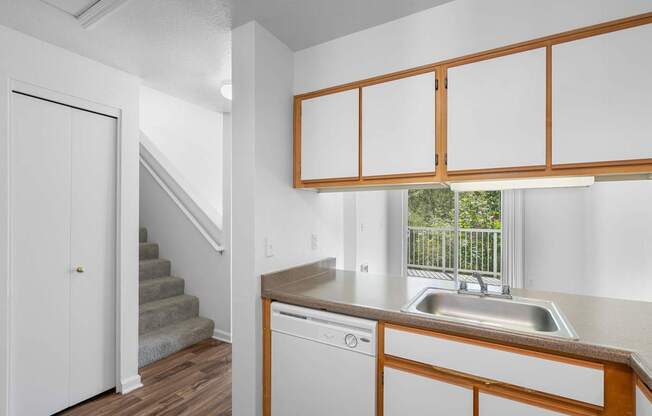 a kitchen with a sink and a window and a staircase