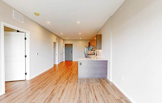 a living room and kitchen with wood floors and white walls