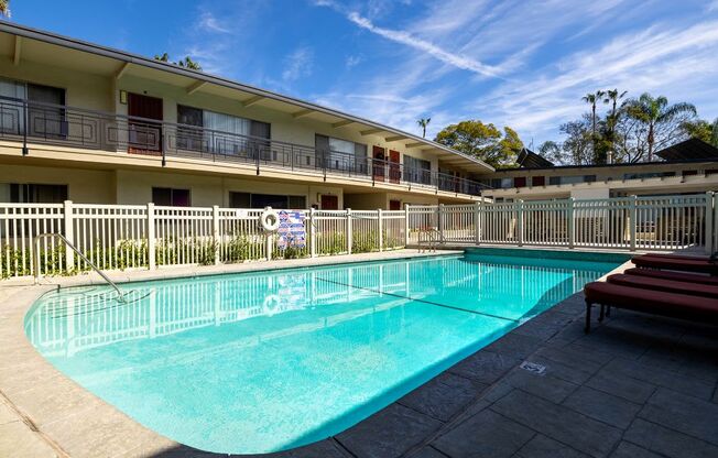 A swimming pool in front of a building with a fence around it.