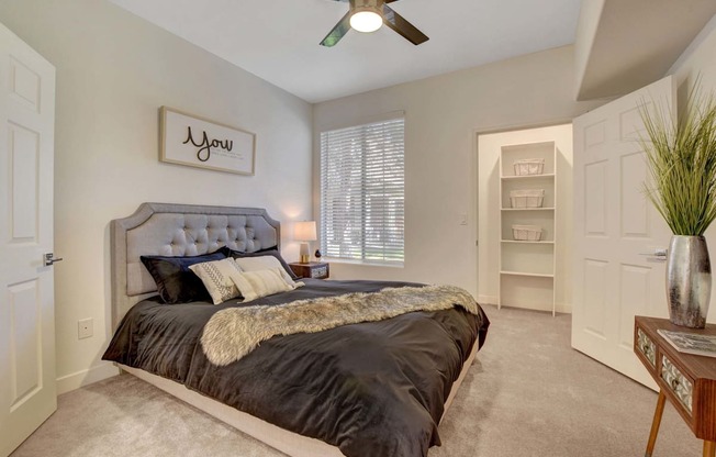 A bedroom with a large bed and a ceiling fan.