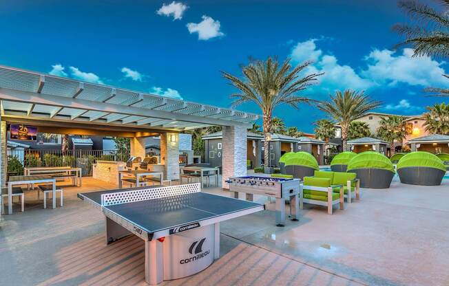 A pool table is in the middle of a patio with a table and chairs around it.