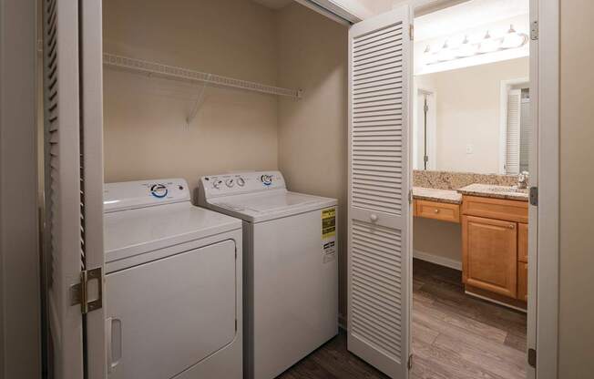 A hallway laundry room closet with white full size washer and dryer appliances