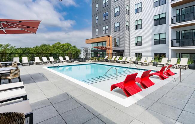Resort-inspired poolside seating with bold red loungers at Modera LoSo.