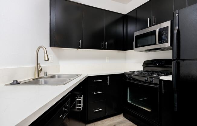 a kitchen with black appliances and white counter tops and black cabinets