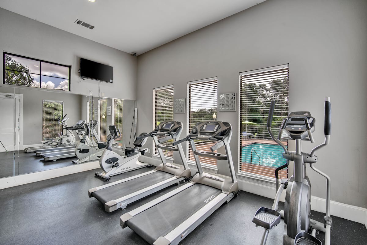 the gym with cardio equipment and windows overlooking the pool
