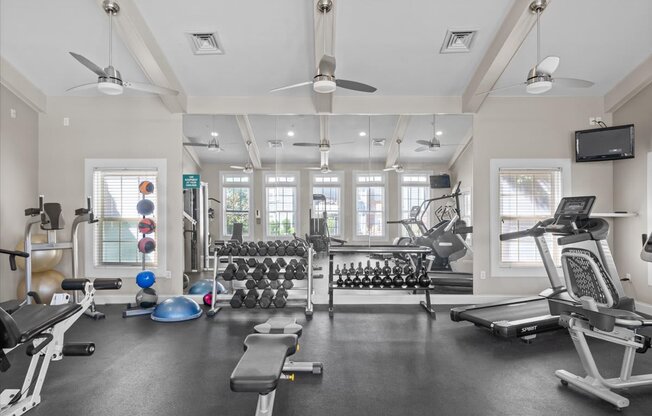 A spacious gym with a variety of equipment including treadmills, weights, and a television. at Somerset Oaks Apartment Homes, Olathe, KS