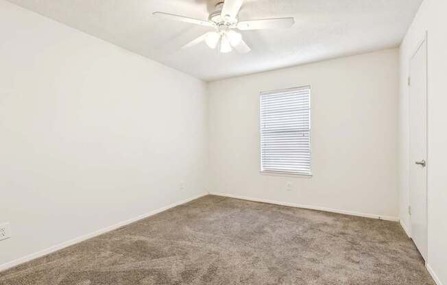 A room with a ceiling fan and carpeted floor.