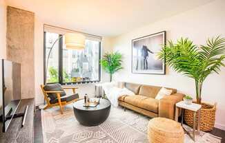 A living room with a brown couch, a coffee table, and a large window.