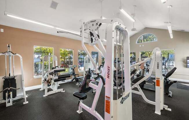 A gym with a variety of equipment including a white weight machine at Clackamas Trails Apartments, Oregon, 97222