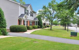 a row of houses on a street with a green lawn