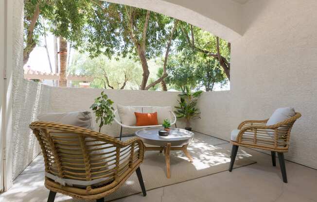 a patio with two rattan chairs and a table