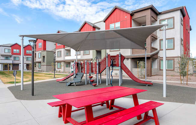 A playground with a red picnic table and slide.