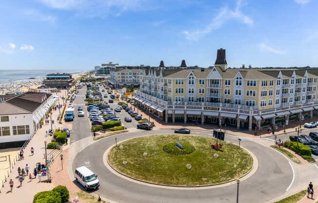 A roundabout with a grassy island in the middle is surrounded by buildings and cars.