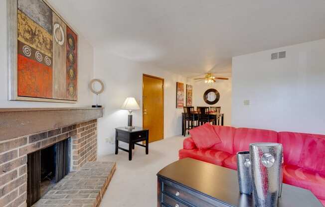 One-bedroom model unit living room at Olde English Village, showcasing a stone-brick fireplace and warm, inviting decor.