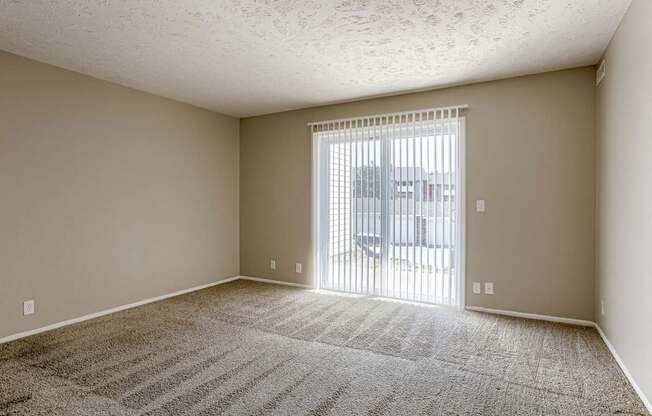 A room with a carpeted floor and a sliding glass door. Omaha, NE Evergreen Terrace Apartments