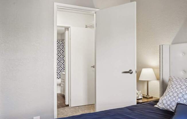 A bedroom with a bed, lamp, and open door.