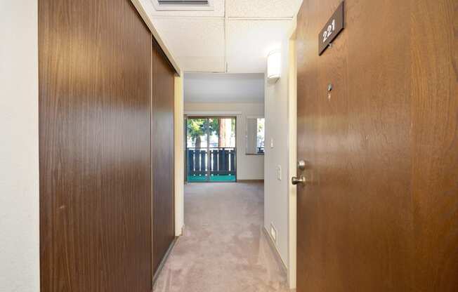 a hallway with a wooden door open to a room with a balcony