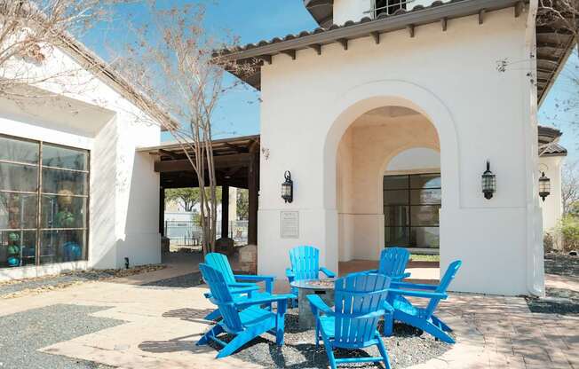 A white building with a blue table and chairs in front.