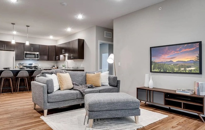 a living room with a couch and a chair in front of a kitchen. Circle Pines, MN Lexington Lofts