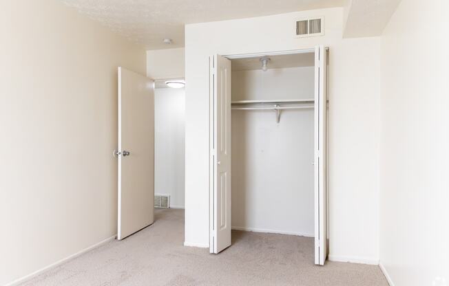 an empty bedroom with a closet and an open door