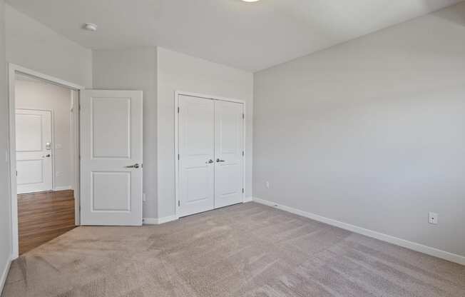 an empty living room with white doors and carpet