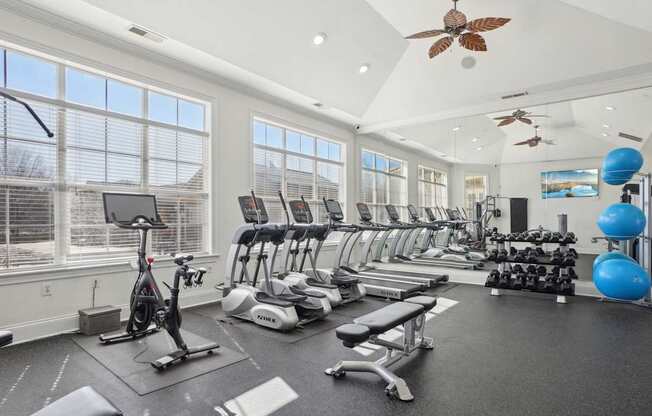 A spacious gym with a variety of exercise equipment and a ceiling fan.
